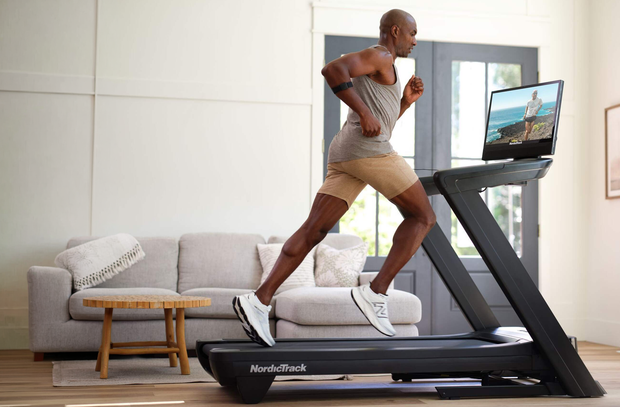 Homme courant sur un tapis NordicTrack 2450 pendant qu’un entraîneur iFIT apparaît à l’écran.
